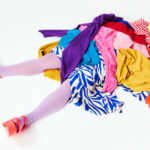 dziewczynka przygnieciona stosem ubrań